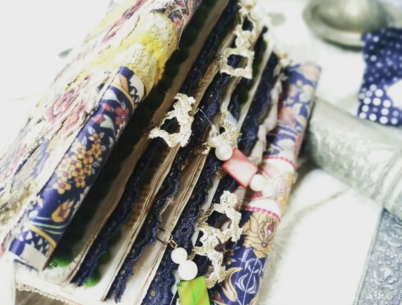 A handmade junk journal with navy lace-edged pages, pearls and blue floral fabric