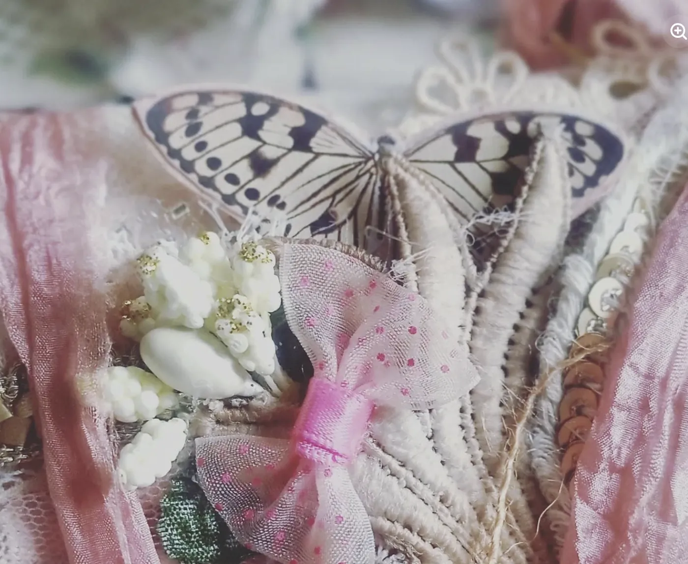 A paper butterfly and white blooms above a pink bow