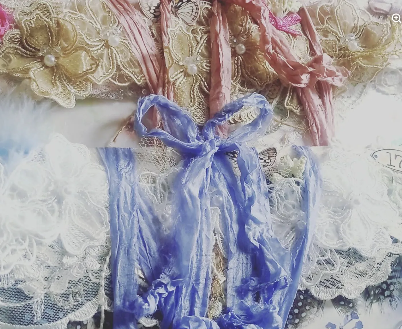 Blue silk ribbon tied over gold embroidery and lace