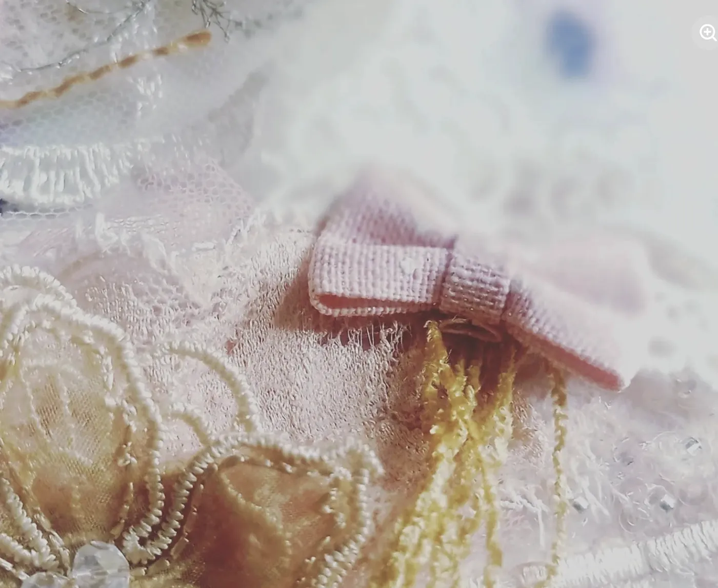 A pink ribbon bow and a soft tassel on vintage lace