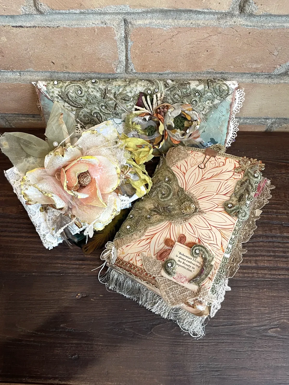 The Book of Garden, After the Wedding and The Birds Remember artist journals arranged together against brick and dark wood