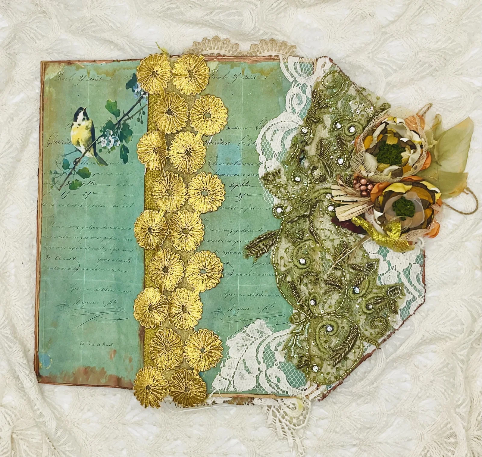The Birds Remember opened flat to show its decorated cover, gold flowers, lace and embroidered textiles
