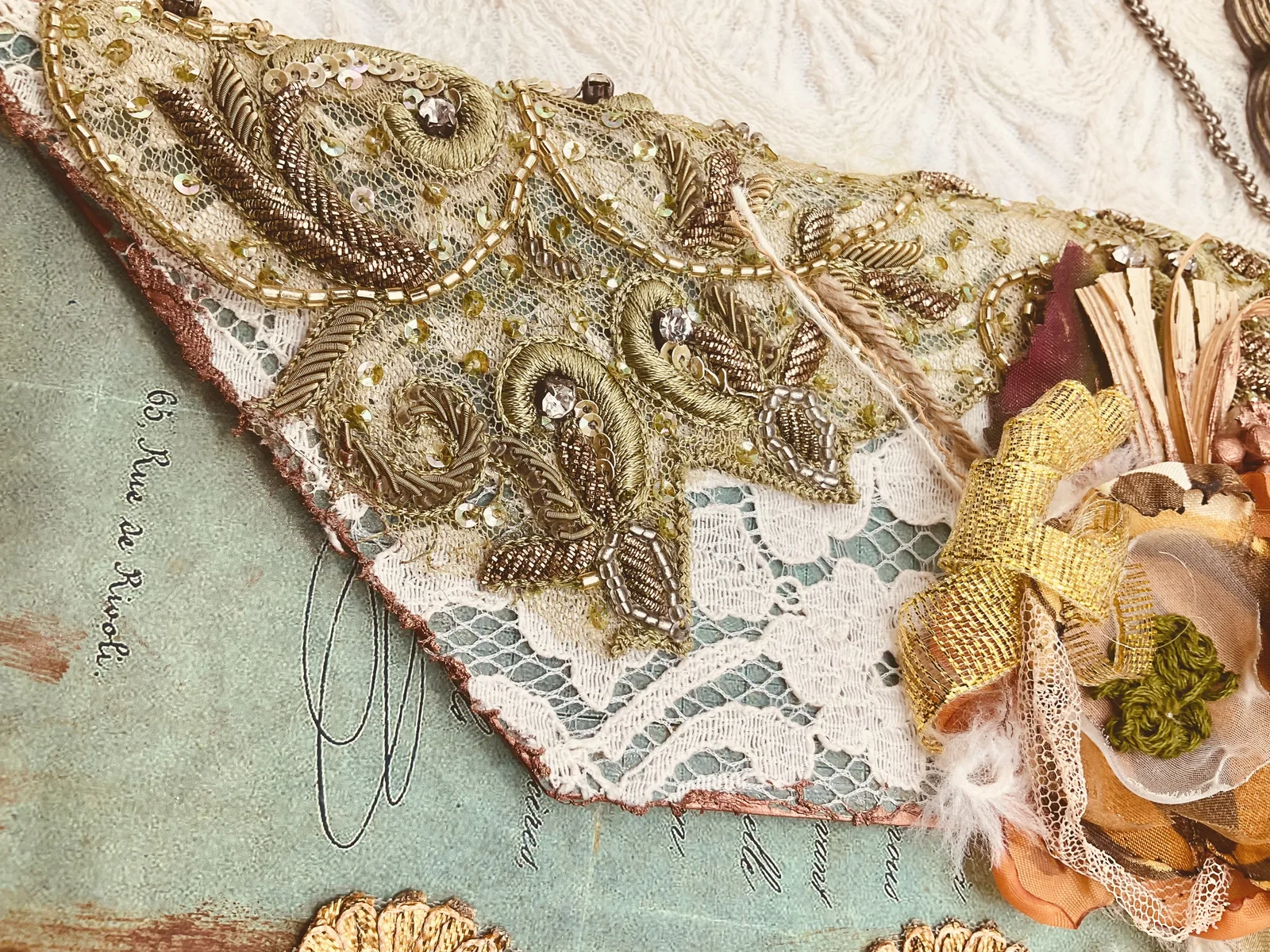 A close detail of gold embroidery, lace and handmade flowers