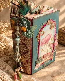 A teal Trinketz journal with a vintage textile spine, lace and a beaded tassel